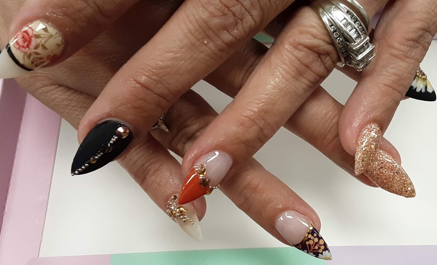 Close-up of a fresh nail set with black, orange, glitter and floral nail art